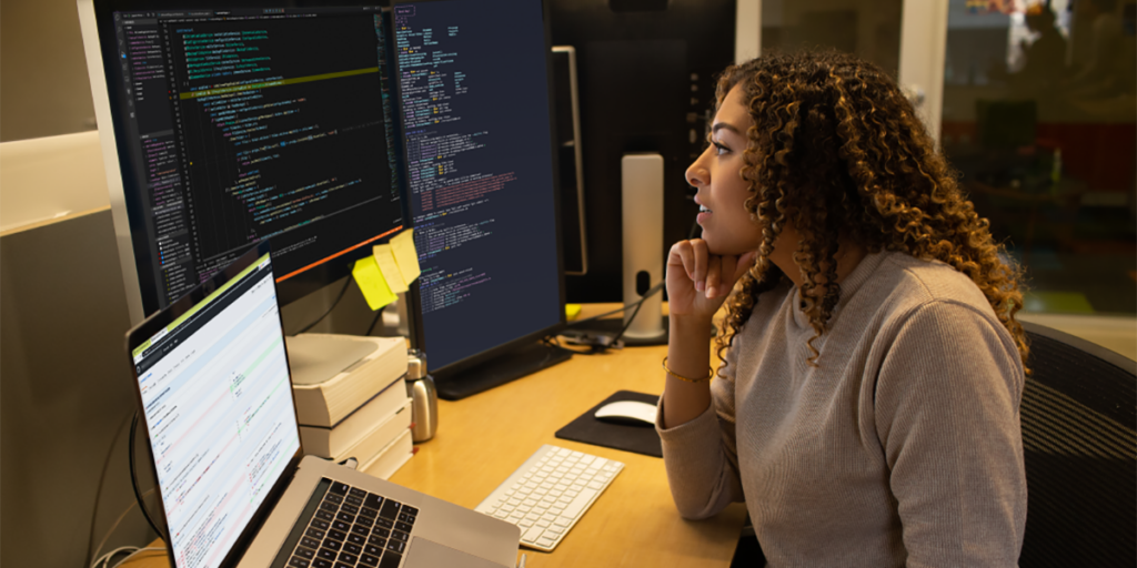 Employee observing information on laptop and screens representing the importance of information protection.